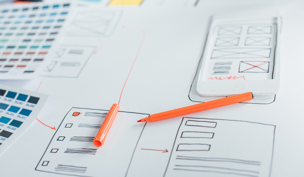 Selective focus of marker on sketches of website design near color palettes on table